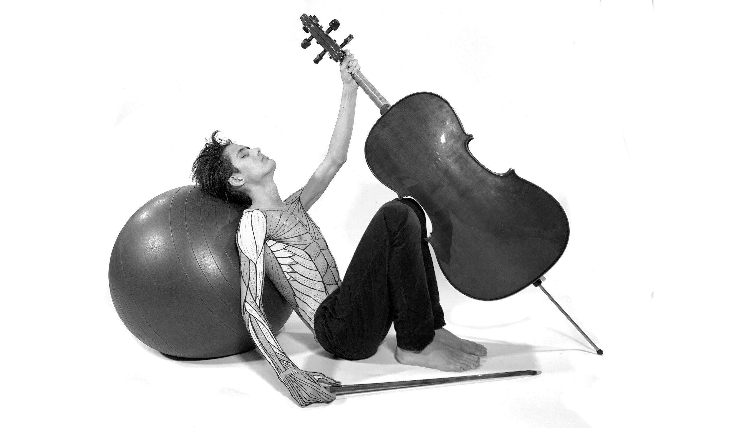 Un violoncelliste au torse dessiné de muscles, adossé à un ballon, lève son violoncelle à bout de bras.