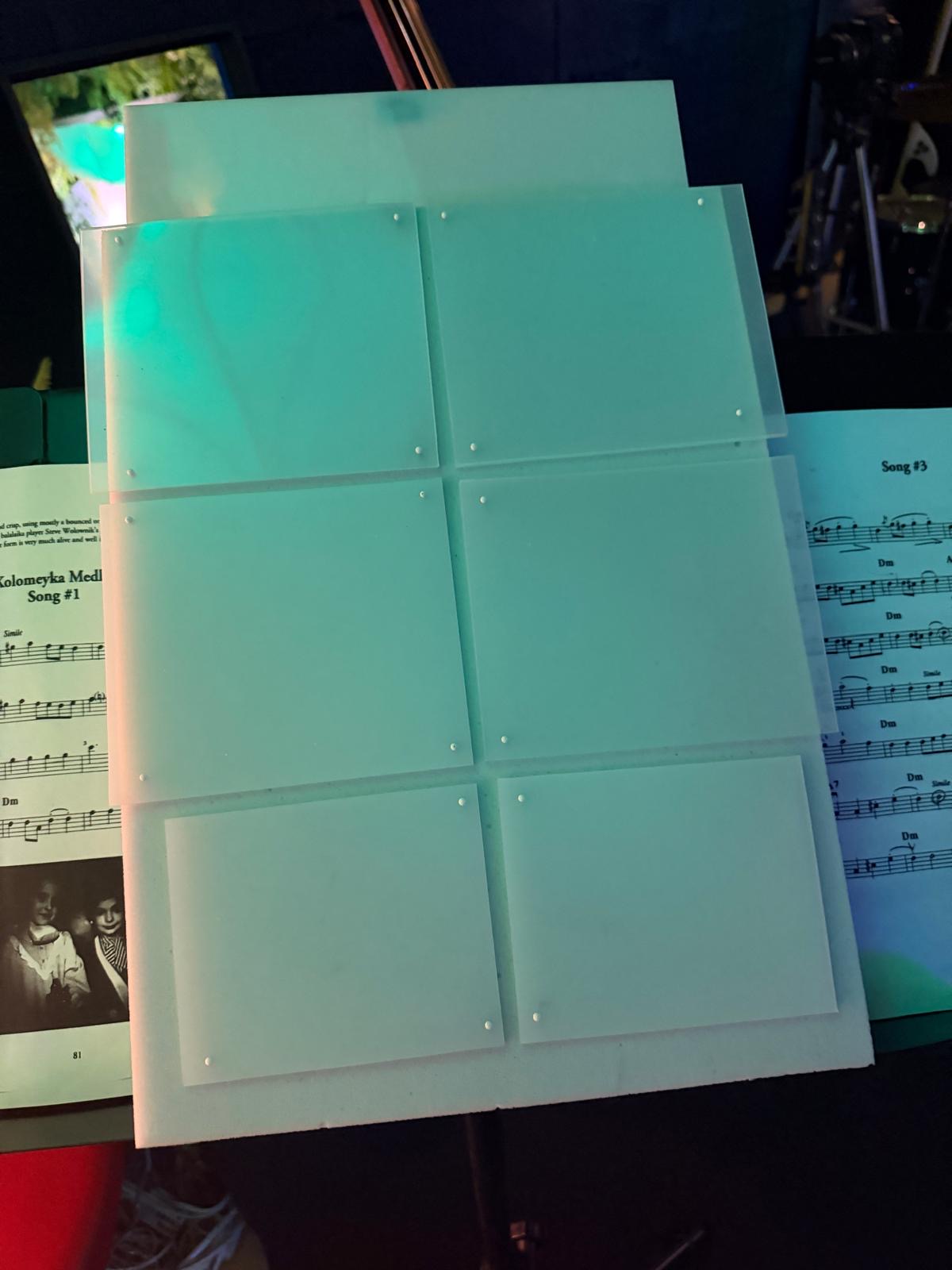 Prototype à six pads translucides posé sur un pupitre, entre deux partitions.