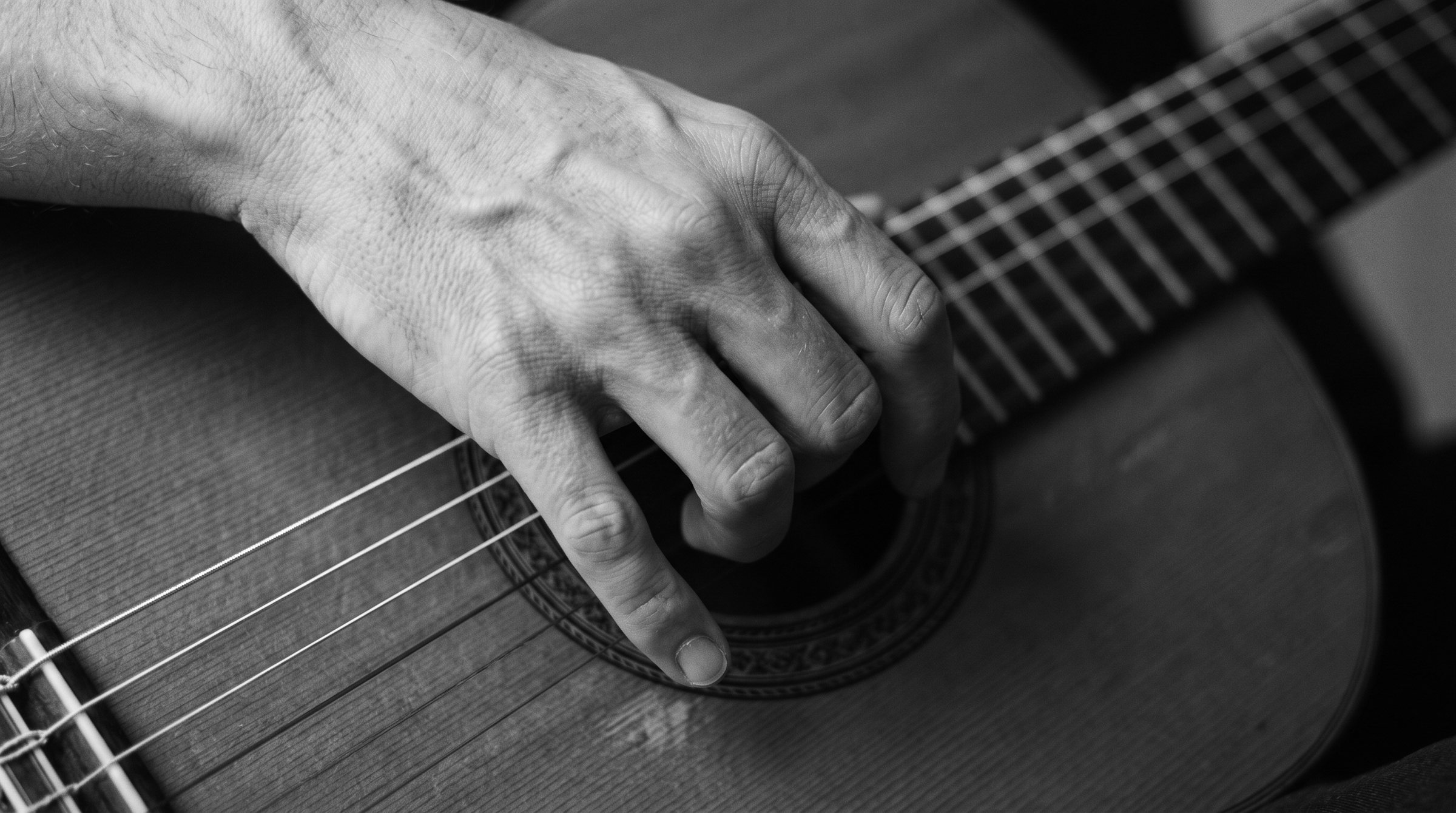 La main droite d’un guitariste au-dessus de la rosace : les doigts se crispent et se referment sur les cordes.