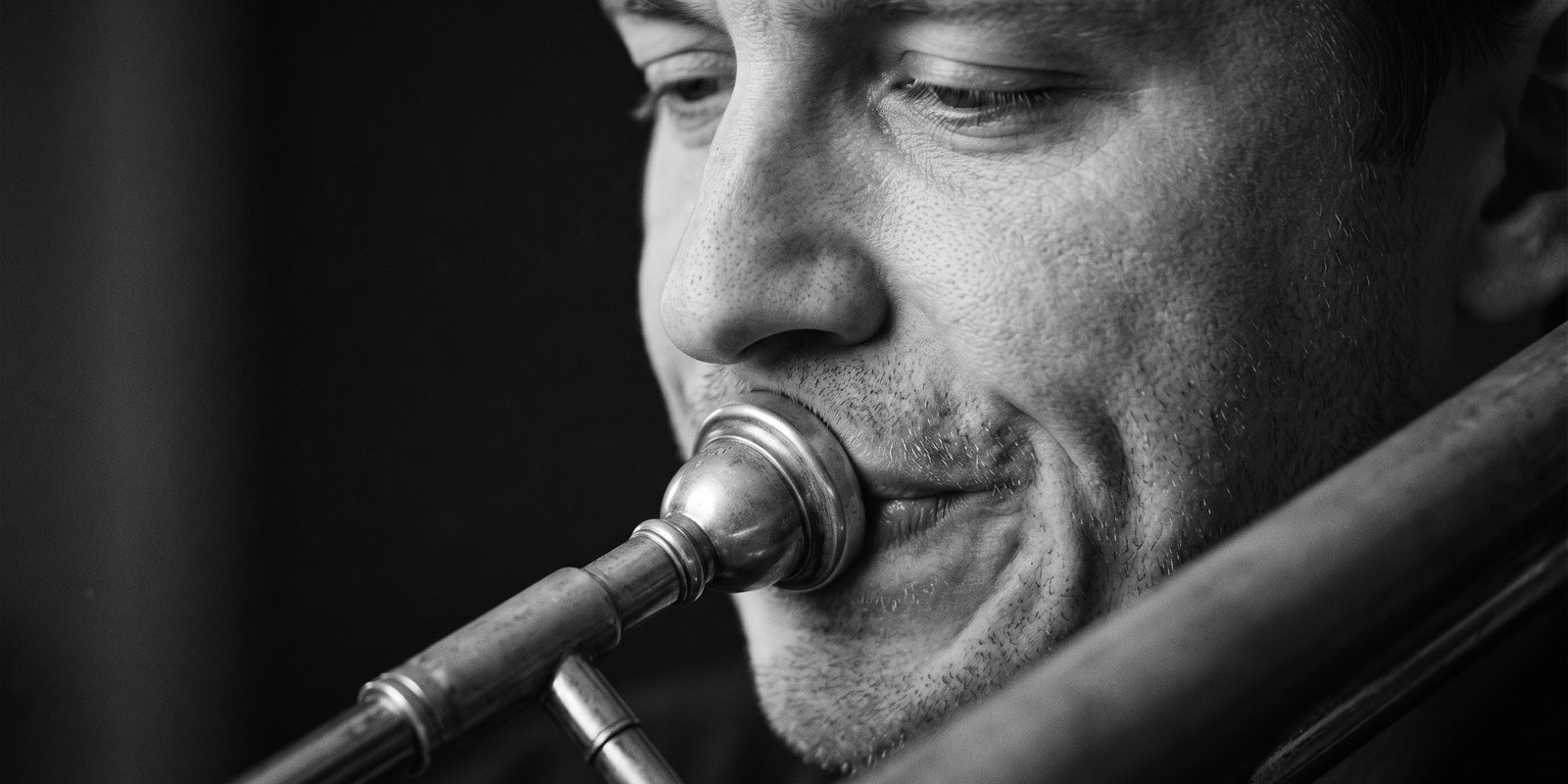 Un tromboniste dans l’effort, l’embouchure décentrée, les muscles des joues tendus.