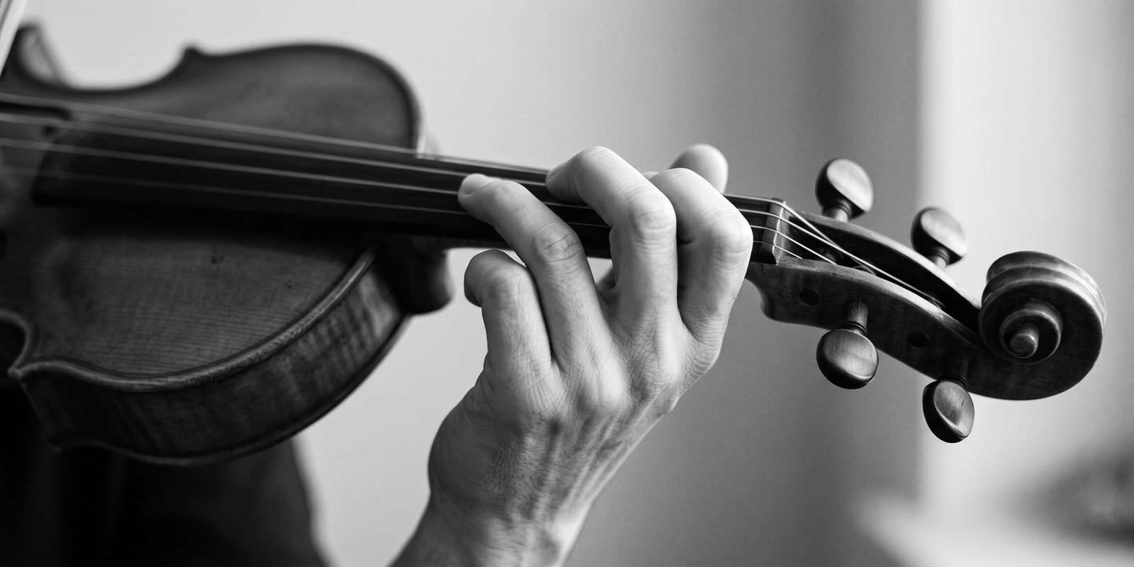 La main gauche d’un violoniste sur le manche : deux doigts restent repliés sous la touche.